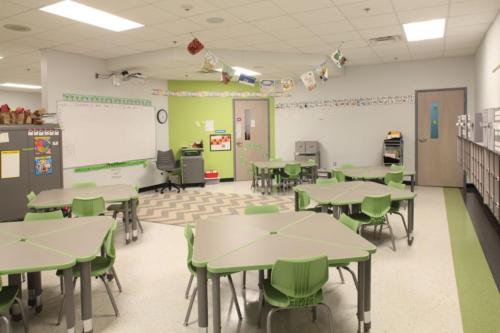 A classroom with green and brown triangular desks put together into squares