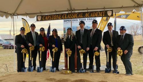 People in hard hats hold shovels at the Capstone Classical Academy ground breaking ceremony
