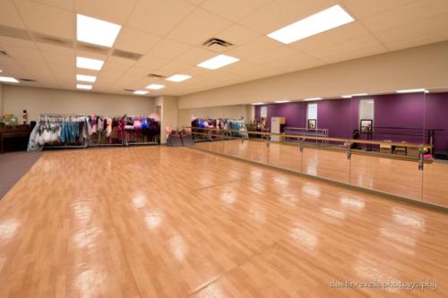 dance studio with mirrored walls and dance outfits on racks