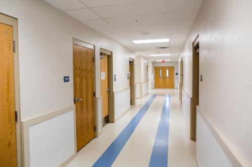 View down a school hallway with blue stripes in the tile floor