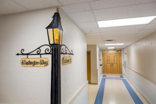 Hallway with a lamp post with street names painted on the corner of the wall