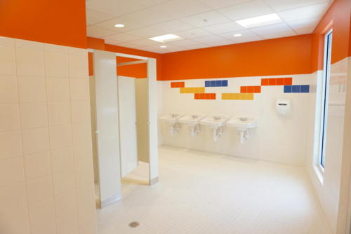 A bright restroom with orange, blue and yellow tiles