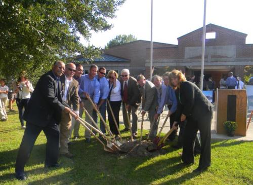 People posing with shovels in the dirt at the school groundbreaking ceremony