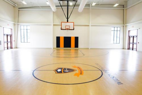 Half court of the school basketball court with a hoop in the background