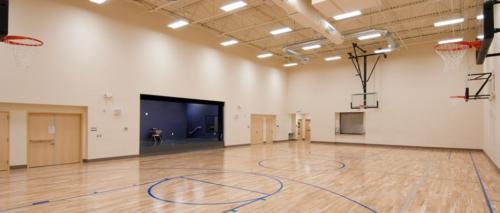 A school gym with several basketball hoops and a stage