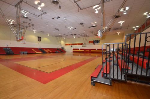 The school gym and basketball court with red and black bleachers