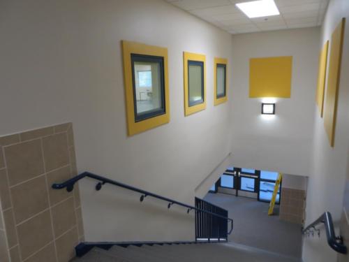 Looking down a stairway with bright yellow accents on the walls
