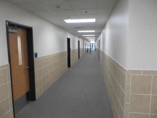 A long, carpeted hallway with students walking into class