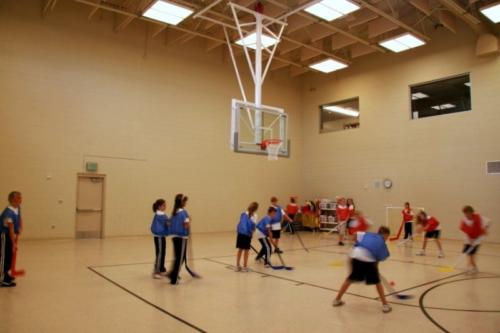Students playing hockey on foot inside the school gym