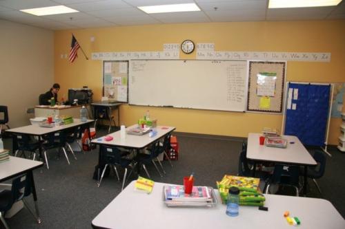 A classroom with a teacher working in the corner of the room