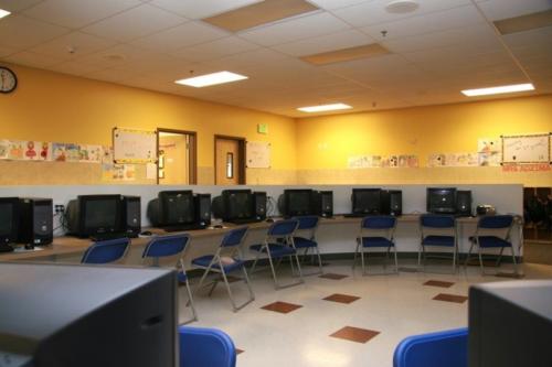 A computer lab with blue chairs and yellow walls
