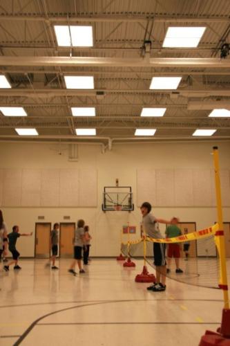 Children setting up volleyball nets inside the school gym
