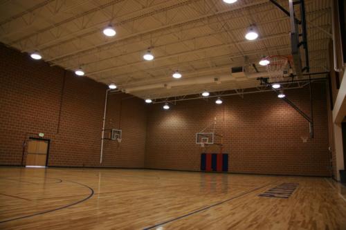 A large school gym with brick walls and several basketball hoops