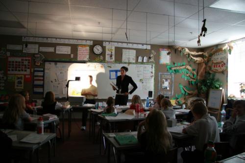 A teacher standing near a student and an overhead projector