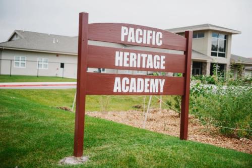 A wooden sign on the school property that reads "Pacific Heritage Academy"