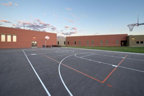 A full outdoor basketball court behind the school